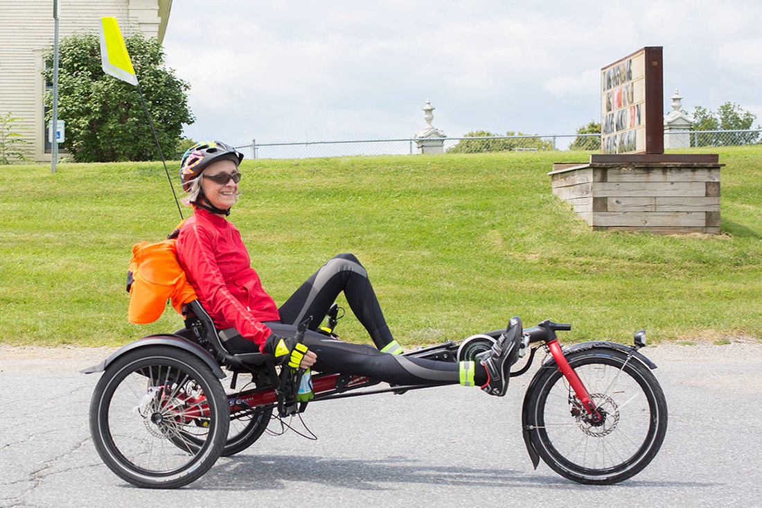 Smiling woman riding a Hase Kettwiesel recumbent trike